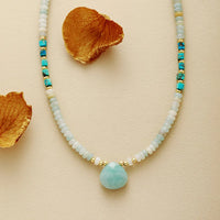 Necklace with Amazonite pendant and gold accents on a beige background