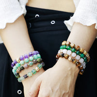 Close-up of hands wearing multiple beaded bracelets on a plain background. Faceted Cube Bracelet | ALLORA JADE
