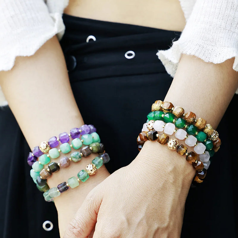 Close-up of hands wearing multiple beaded bracelets on a plain background. Faceted Cube Bracelet | ALLORA JADE