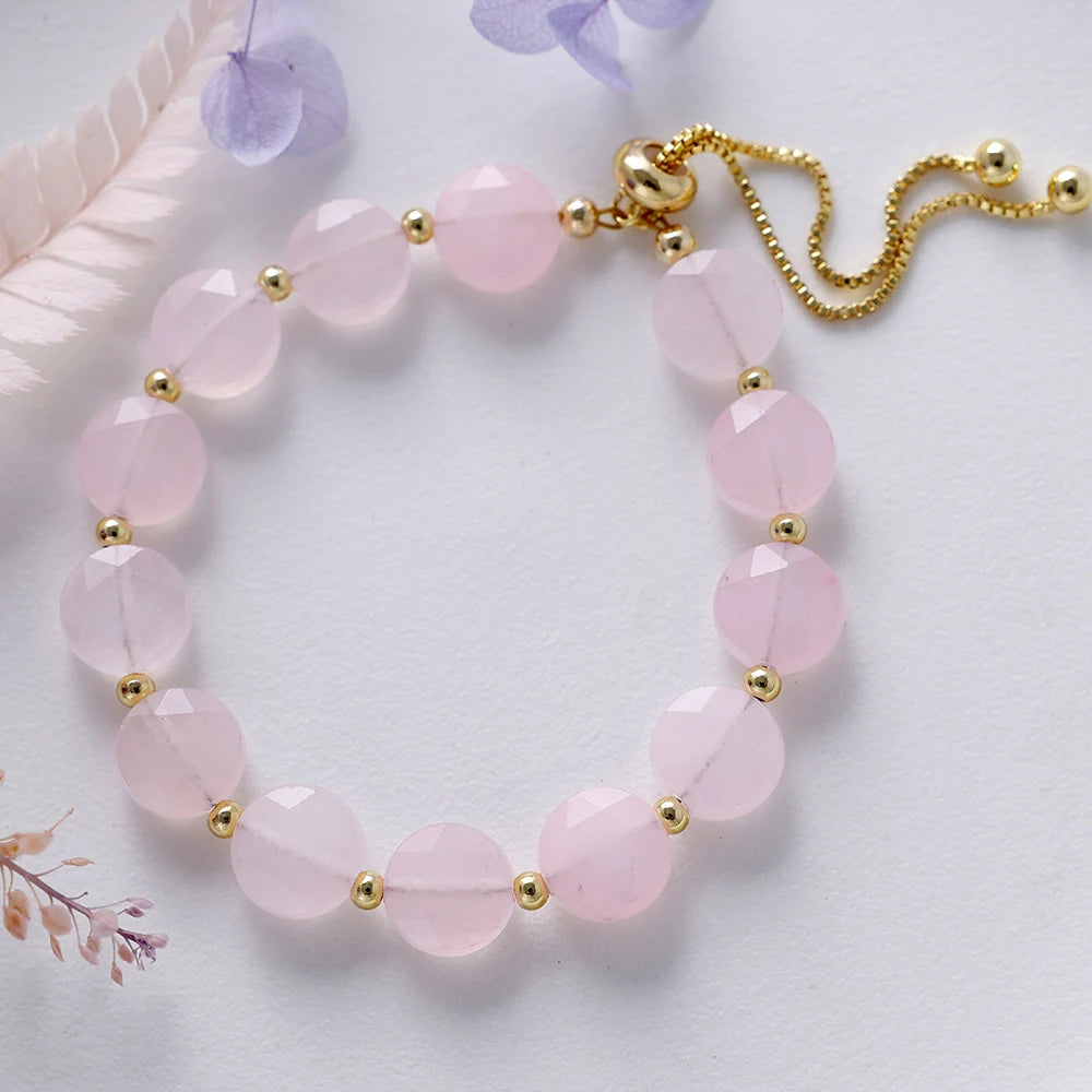 Pink beaded bracelet with gold accents on a light background
