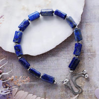 Blue beaded bracelet with silver accents on a textured surface