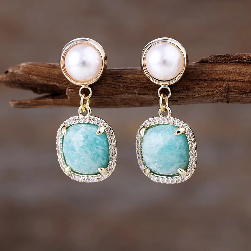 Amazonite Pavé Cushion Dangle Earrings featuring ocean blue gemstone drops framed by sparkling rhinestones, with imitation pearl studs in gold-coloured settings, displayed on rustic wood.