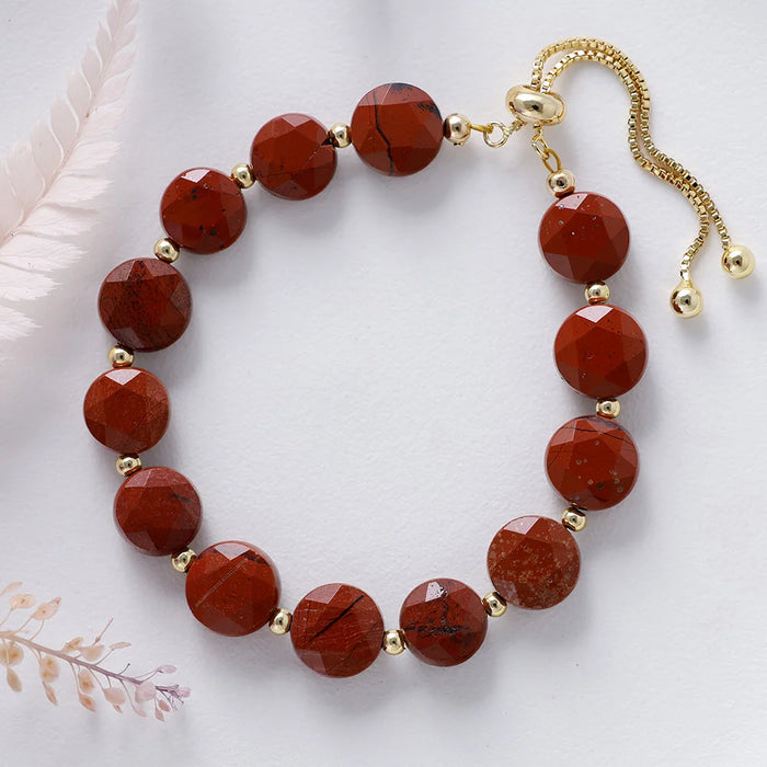 Bracelet with red Jasper beads and gold accents on a white background