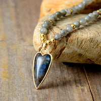 Necklace with a heart-shaped labradorite pendant on a stone surface