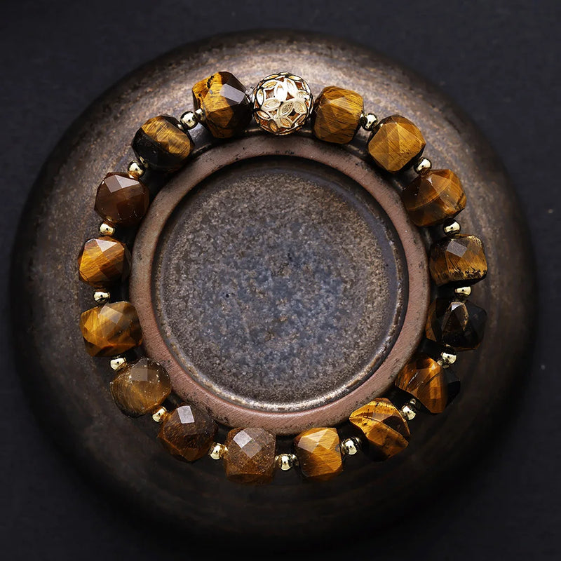 Bracelet with brown beads on a dark surface. Tiger’s Eye Faceted Cube Bracelet | ALLORA JADE