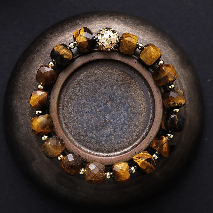 Bracelet with brown beads on a dark surface. Tiger’s Eye Faceted Cube Bracelet | ALLORA JADE