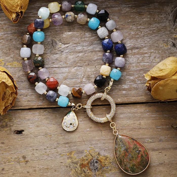 Multicolored beaded Necklace with gold charm on a wooden surface. Chakra Crystal Pavé Statement Necklace | ALLORA JADE