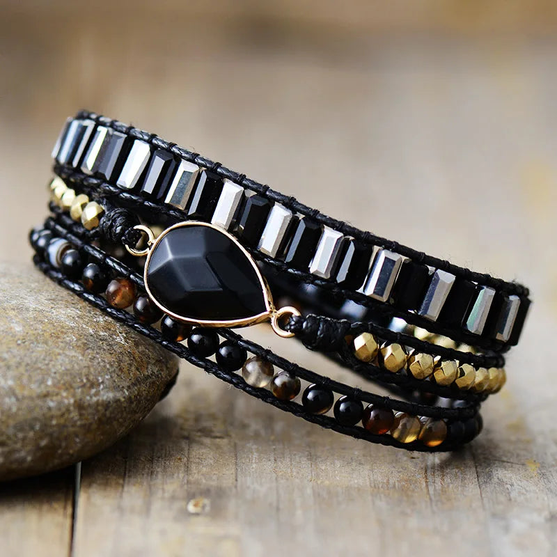 Multi-layered bracelet with beads and stones and Black Onyx Charm, displayed on a stone surface