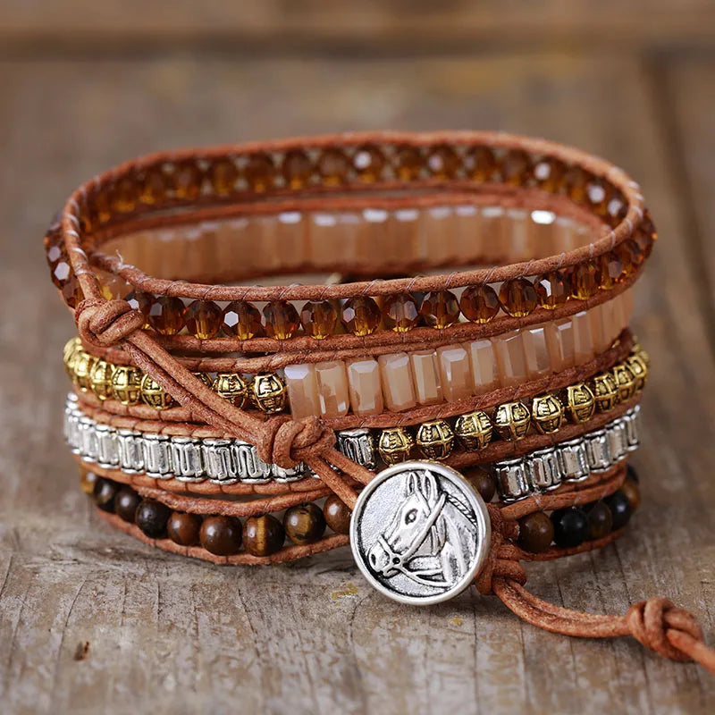 Multistrand brown, silver and gold beaded bracelet with horse charm on a wooden surface