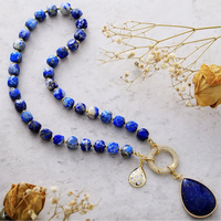 Blue beaded necklace with gold accents and pendant on a marble surface and with dried flowers. Lapis Lazuli Pavé Statement Necklace | ALLORA JADE