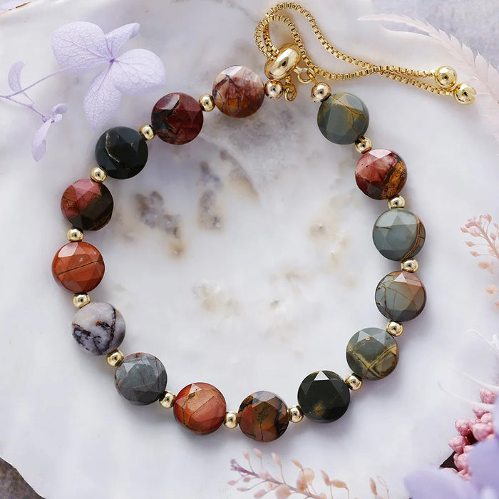 Multicolored beaded bracelet on a marble surface with decorative flowers.