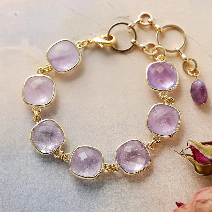 Gold bracelet with pink gemstones on a light background