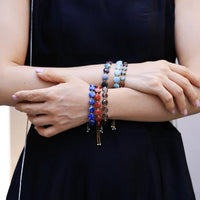Close-up of a person wearing colorful beaded bracelets on a blurred background
