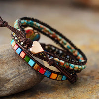 Multicolored beaded bracelet with a heart charm on a stone surface