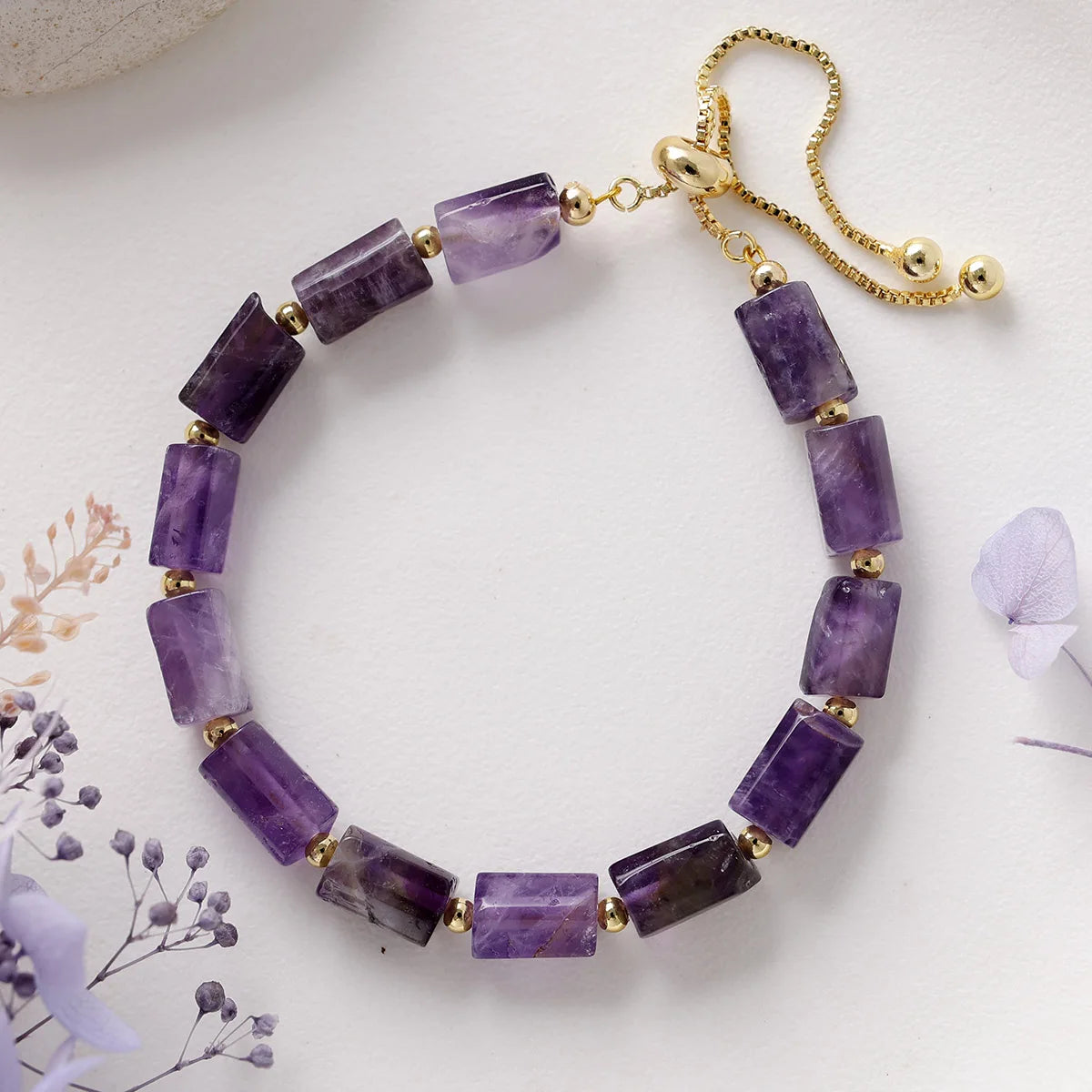 Purple beaded necklace with gold chain on a white background
