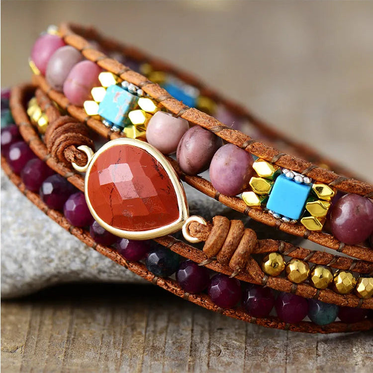 Multicolored beaded bracelet with Red Jasper charm, displayed on a textured surface