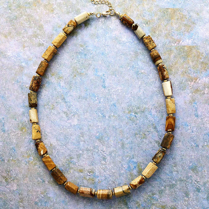 Necklace with brown and beige beads on a textured blue background. ALLORA JADE