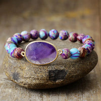 Bracelet with purple stone and colorful beads on a stone surface