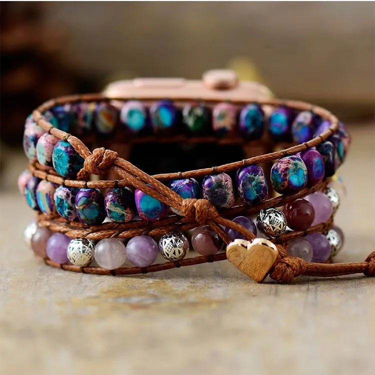 Smartwatch with a colourful beaded strap, with a heart button clasp on a textured surface